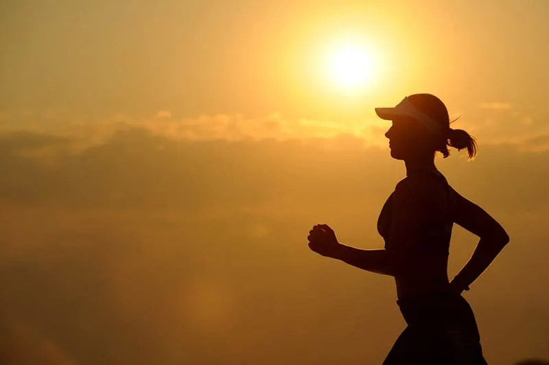 Silhouette of running woman with sunset background