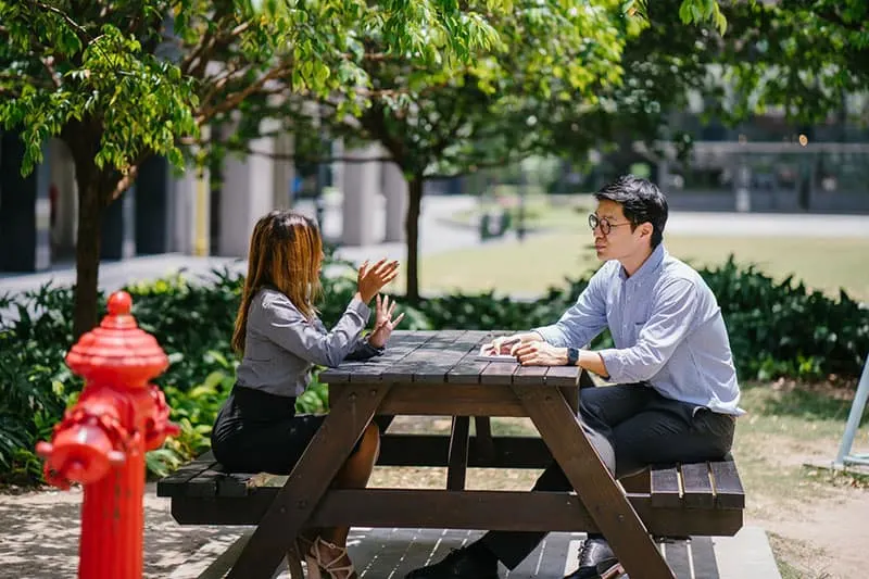 woman talking to a man in office uniforms chatting on benches outside
