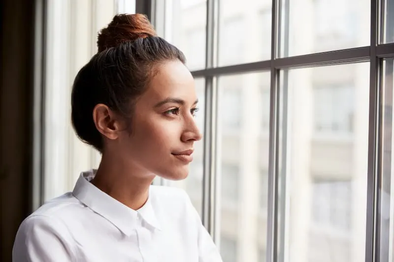 woman with hair bun looking out of window
