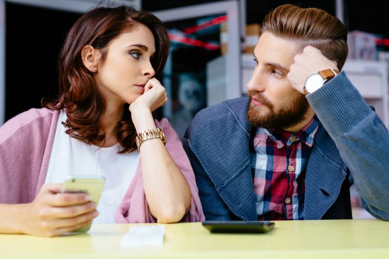 worried couple looking at each other at cafe
