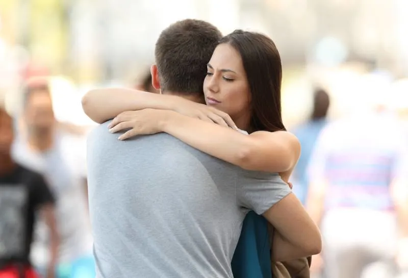 worried woman hugging her boyfriend outside