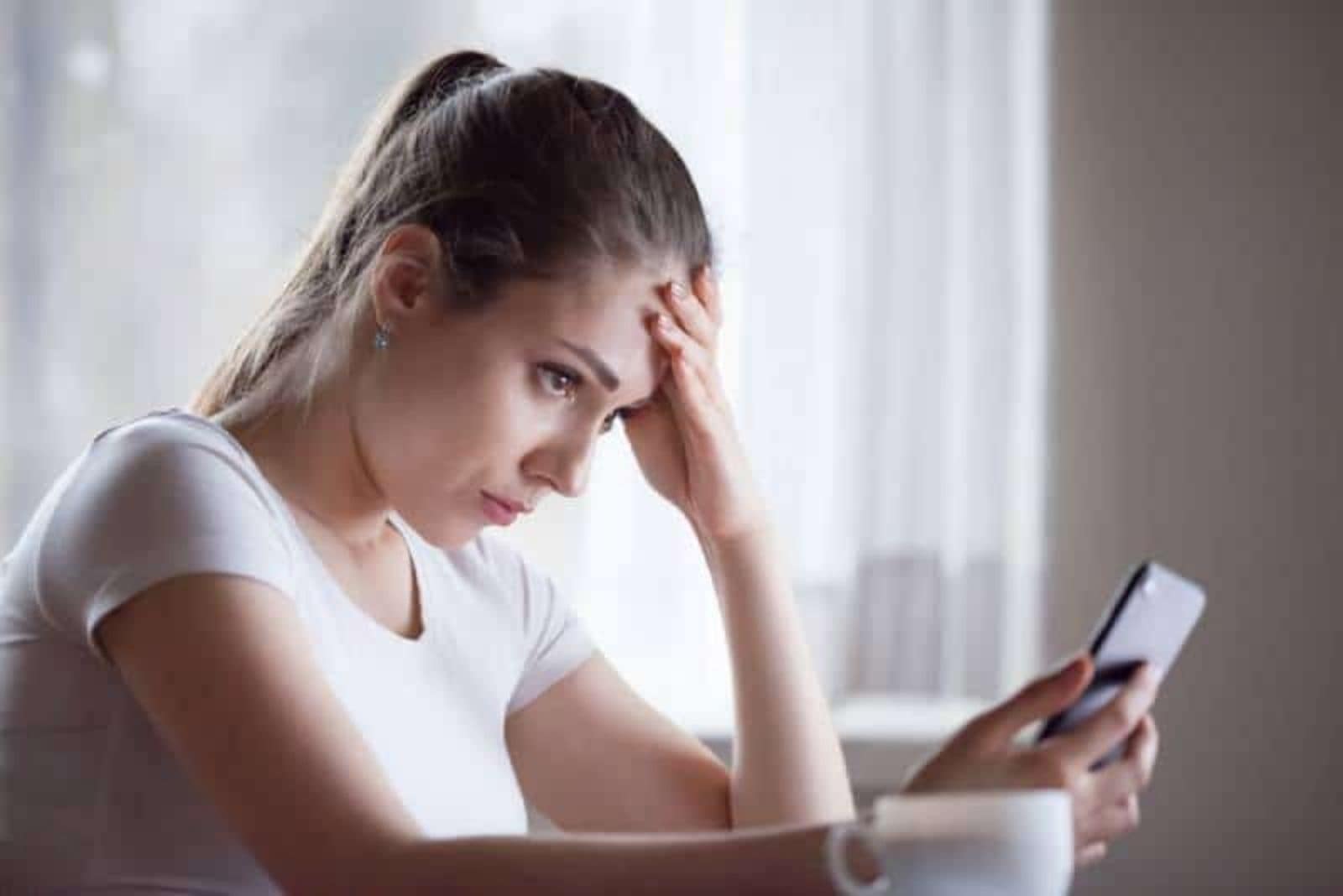 mujer preocupada mirando el teléfono en su casa