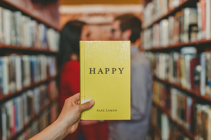 yellow book with title happy in front of couple standing in library