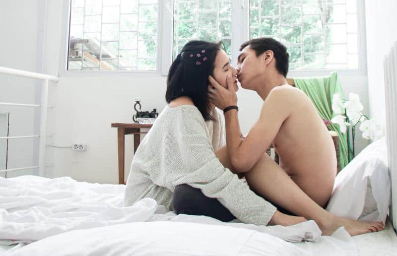 Young woman and man kissing in bed