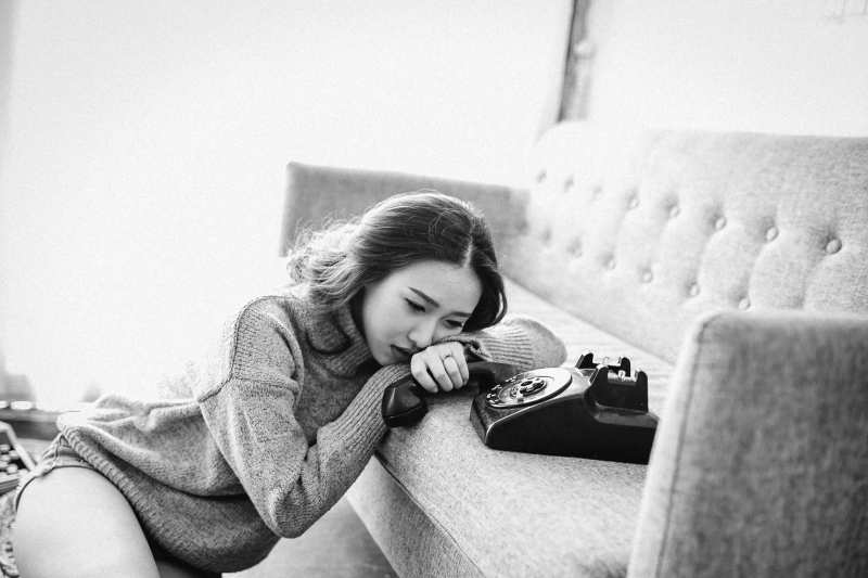 Mujer joven llorando con la cabeza en la sofa y el teléfono en la mano