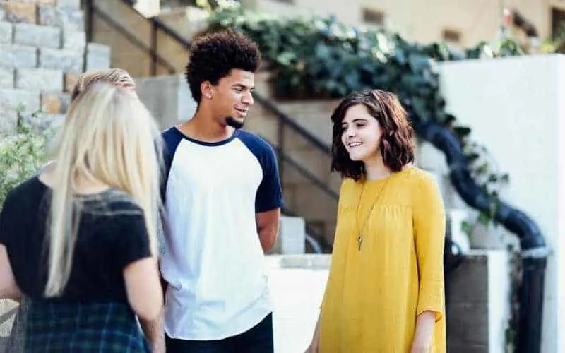 Young woman in yellow dress talking with man and woman
