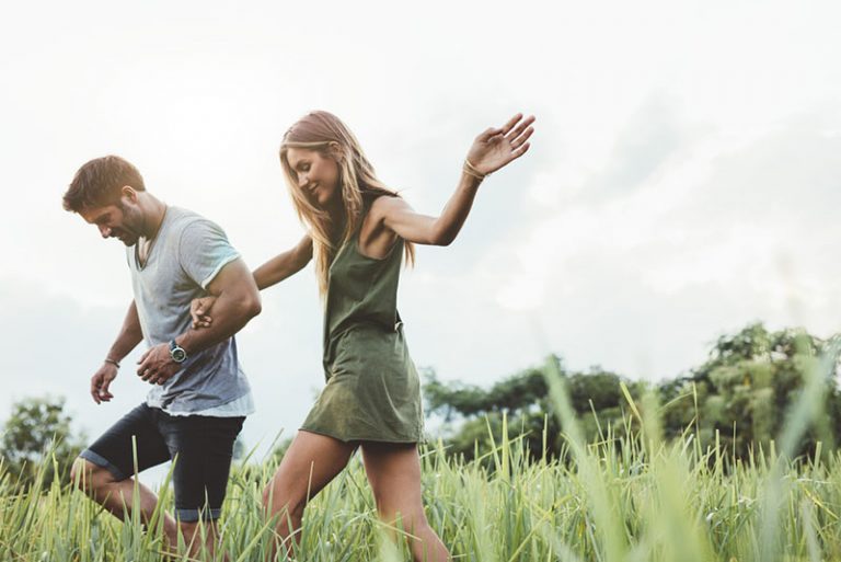 happy couple walking through the grass