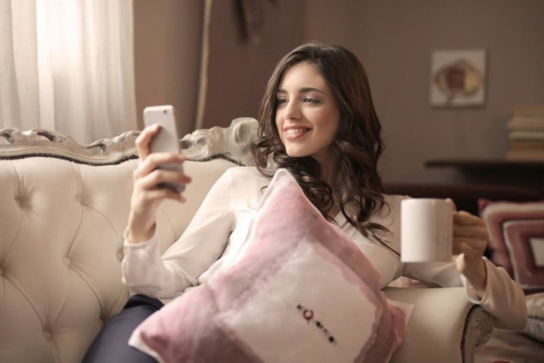 woman looking at phone while sitting on tufted sofa