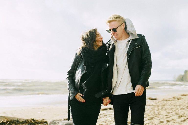 man and woman wearing jackets near seaside under cloudy sky