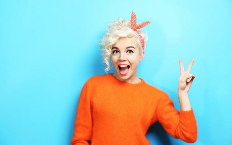 Happy funny woman standing against blue wall