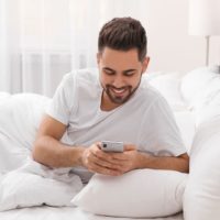 happy man in bed reading a message