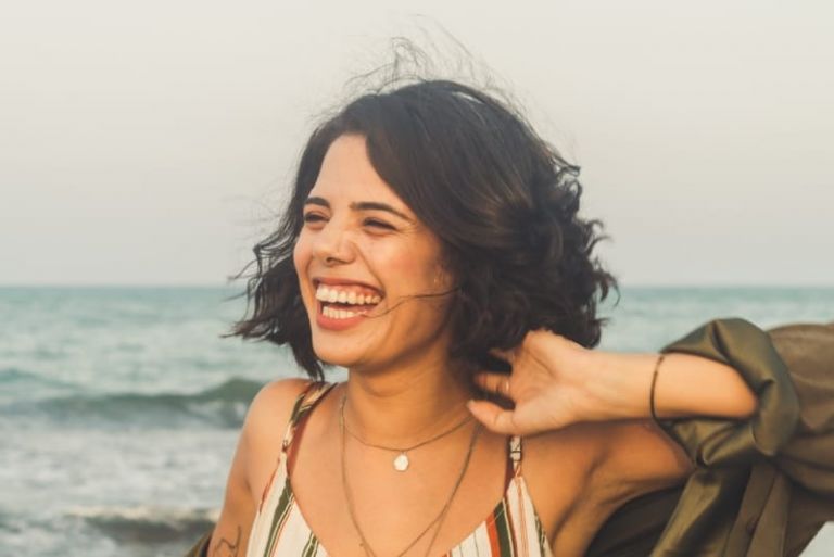 woman in striped top laughing while touching her hair