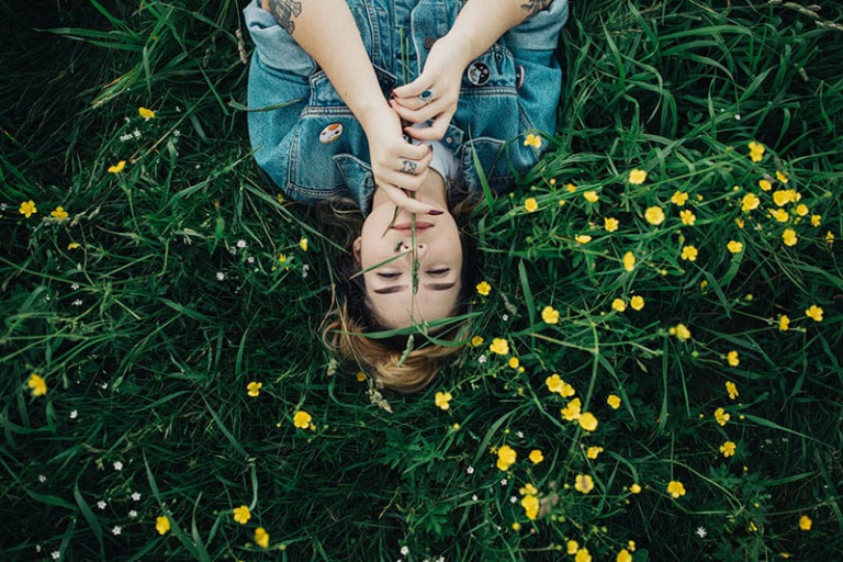 happy woman laying on the grass with flower