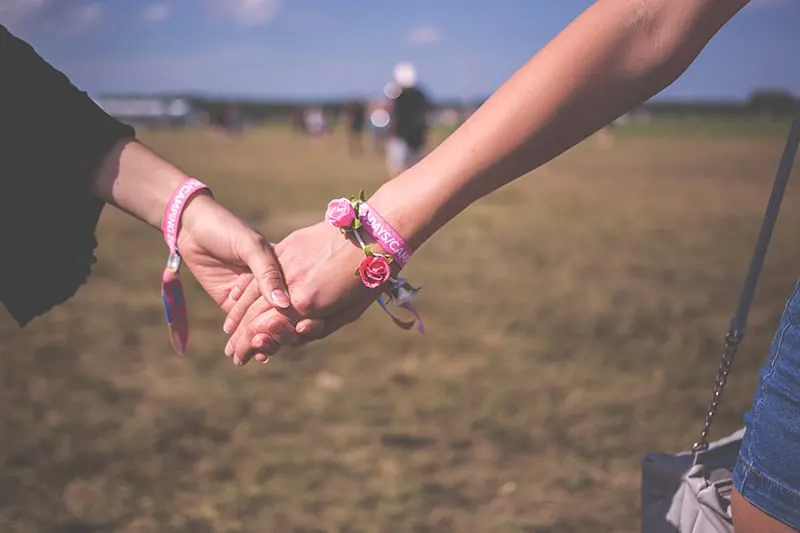 two person holding each other wearing pink friendship bracelet