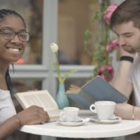 pareja leyendo libros mientras toma café en una mesa cerca de la ventana