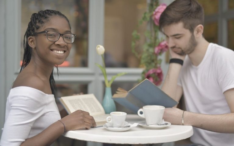 couple reading books while having coffee at a table near the window