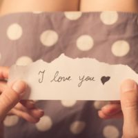 Woman hand holding paper with I love you message