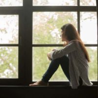 woman sitting near window and looking outside