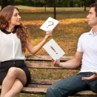 Woman with question mark sign near man with exaclamation mark sign sitting on a bench