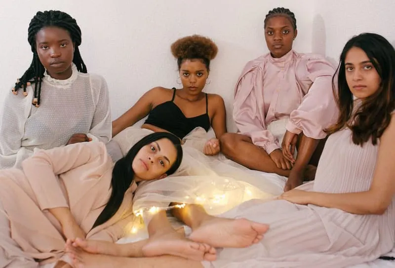 5 women sitting and lying in bed looking sad