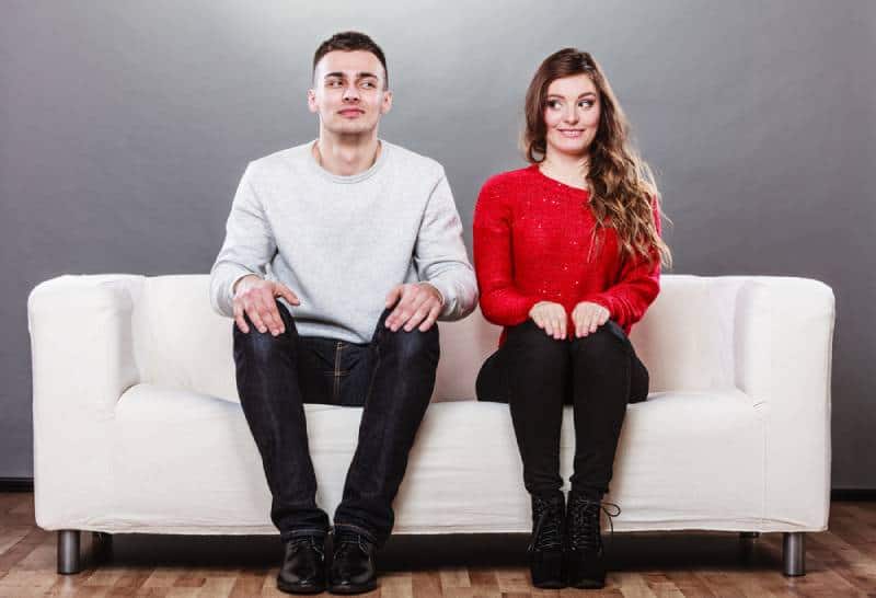 shy couple looking at each other while sitting on sofa couch