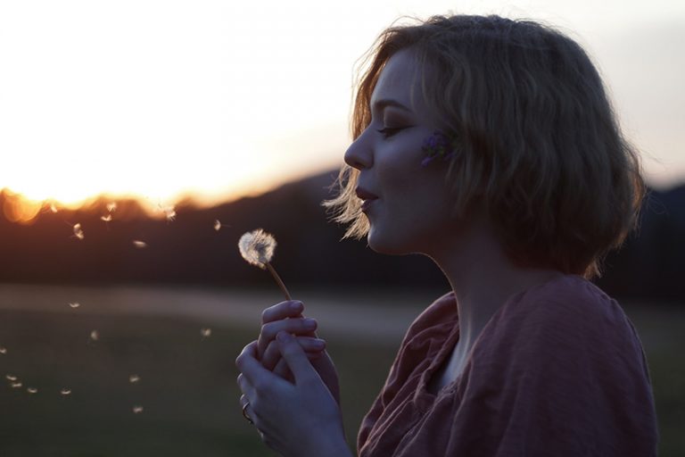 woman blowing dandelion flower