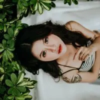 woman lying dressed in a bath near plants