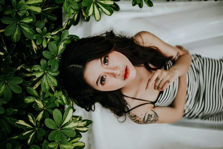woman lying dressed in a bath near plants
