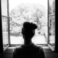 donna triste in piedi davanti alla finestra
