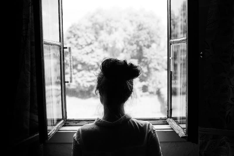 sad woman standing in front of window
