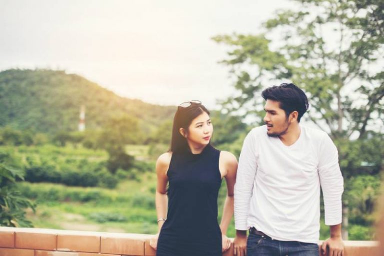 couple leaning on fence outside and looking at each other
