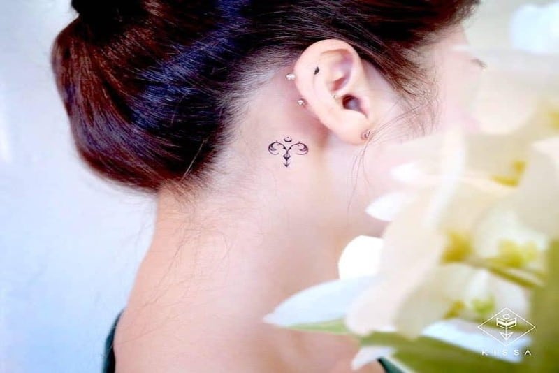 A tiny Aries tattoo behind the ear