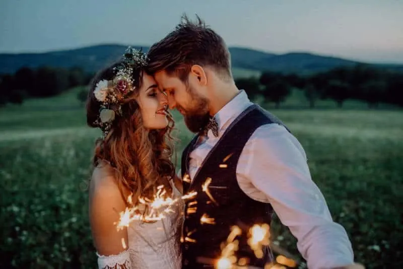 Beautiful bride and groom with sparklers in a meadow.