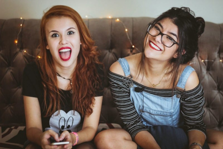 two women laughing and sitting on tufted sofa