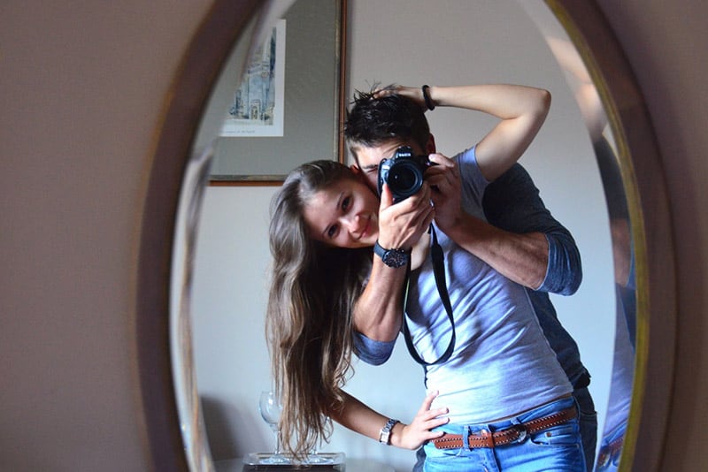 Couple taking own photo using a camera aimed at their mirror reflection