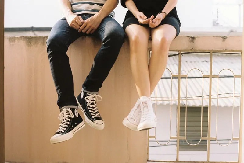 Couple sitting on balcony ledge legs shown