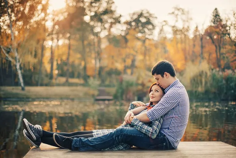 Romantic couple relaxing on the riverdock during autumn