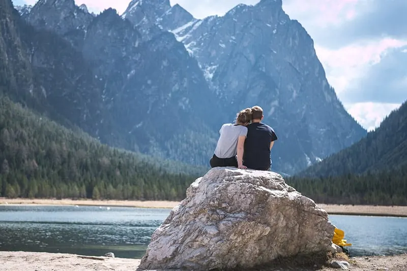 Couple sitting on rock near body of water