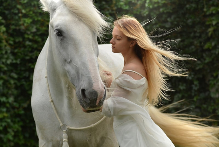 woman in white dress standing near white horse