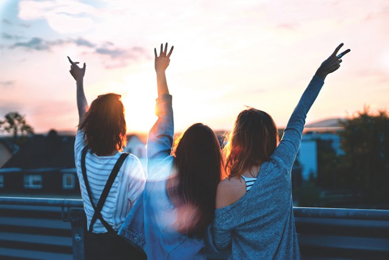 tre donne che alzano le mani durante il tramonto