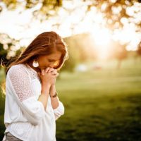 woman praying beside tree