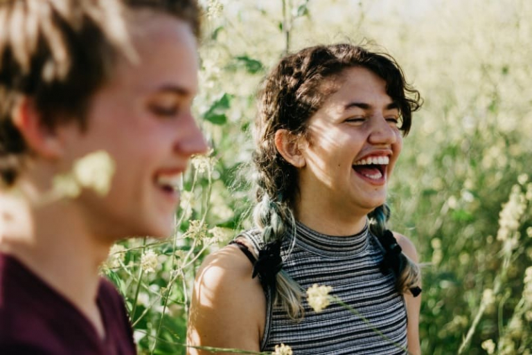 man and woman laughing surrounded with green grass
