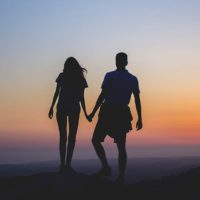 Silhouette of couple holding hands during sunset