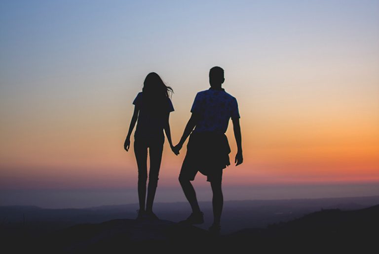 Silhouette of couple holding hands during sunset