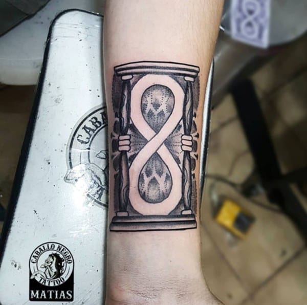 Tatuaggio con simbolo dell'infinito all'interno di una clessidra sul braccio