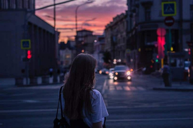 a woman stands on the street with her back turned