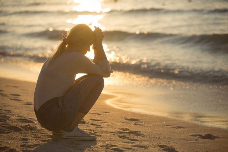 sad woman sitting on the beach