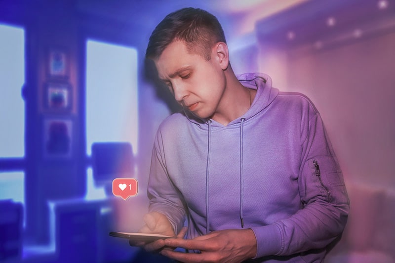 Man wearing a hoodie clicked like heart on social media phone