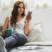 mujer sentada en la cama mientras envía mensajes de texto