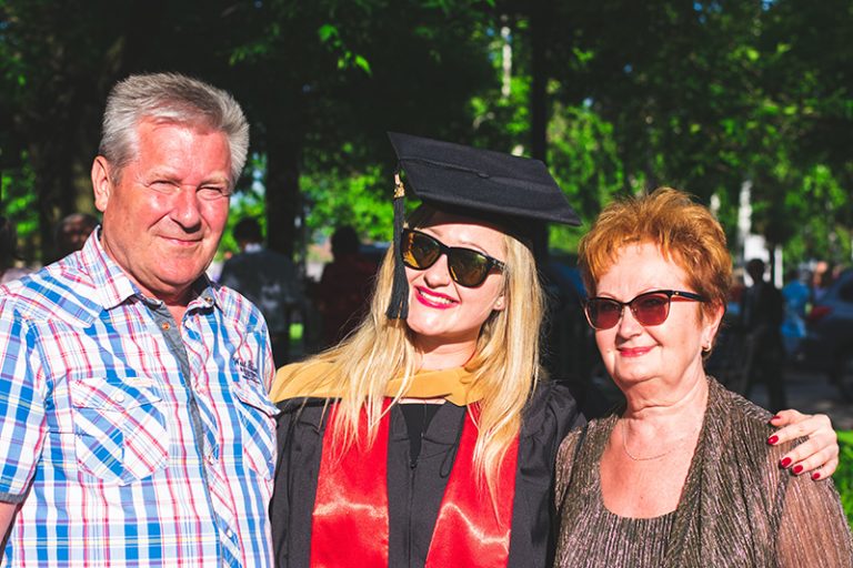 woman wearing academic dress hugging her parents